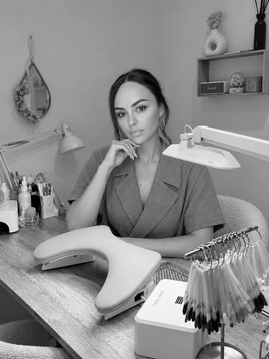 Coralie à son poste de travail, en noir et blanc, une main sous le menton.